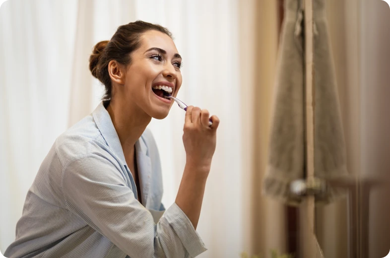 Femme se brossant les dents avec douceur dans le cadre du suivi après une dévitalisation